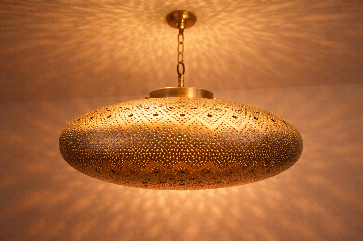 Decorative gold pendant light fixture casting a warm glow on a textured wall.